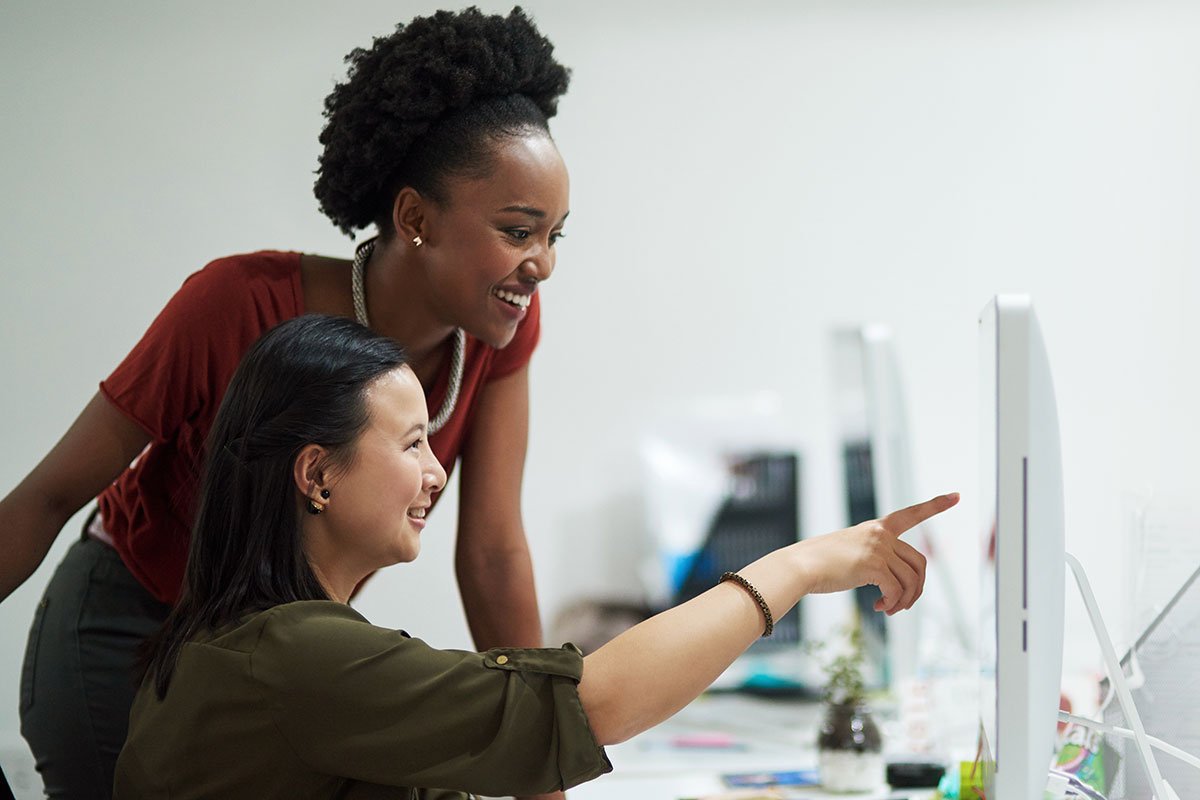 Two women collaborating on ecommerce website design on a computer.