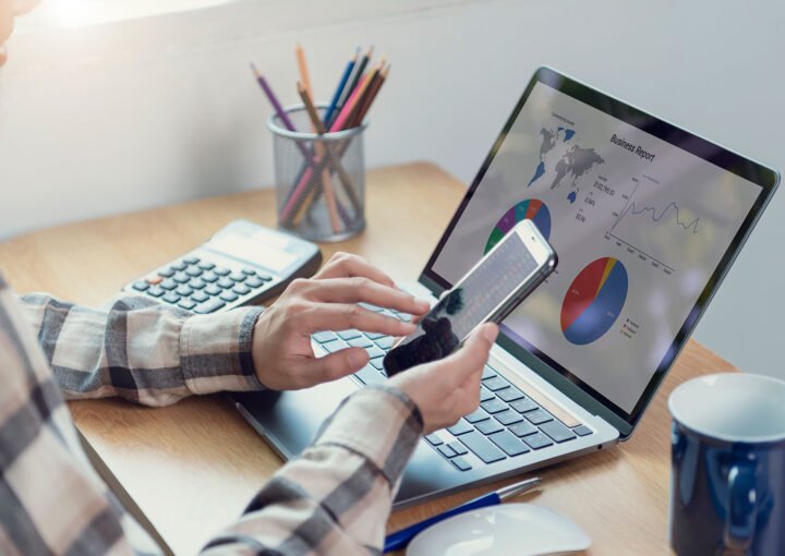 Hands on laptop and phone analyzing business report for SEO friendly web development.