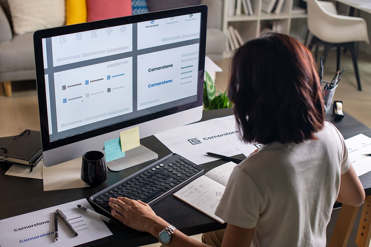Designer working on UI UX design services for "Cornerstone" brand on computer.